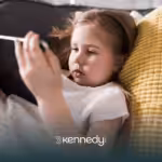 A child laying on a couch while using her mobile tablet