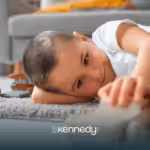 A kid with autism lying on a carpet while holding a wooden toy