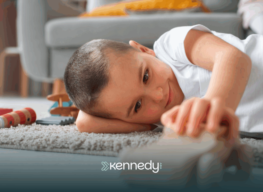 A kid with autism lying on a carpet while holding a wooden toy