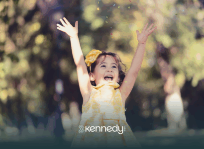 A kid with autism happily raising her arms outdoors