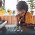 A kid is focused while playing a board game with her siblign