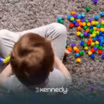 A kid sitting on a carpet, playing with colorful toys