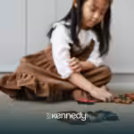 A kid with autism lining up her toy cars on a carpet