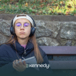 A teenager with autism wearing a cap and headphones sitting outdoors