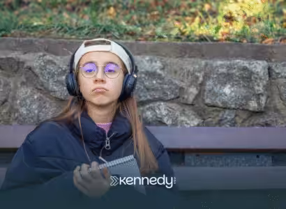 A teenager with autism wearing a cap and headphones sitting outdoors