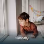 A kid with autism looking from a window alone