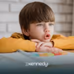 A kid with autism lying his head on a table