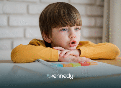 A kid with autism lying his head on a table