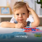 A kid holding a chocolate sitting at a table