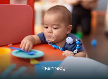 A toddler with a pacifier playing with toys