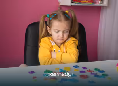 A child with autism sitting at a table looking upset