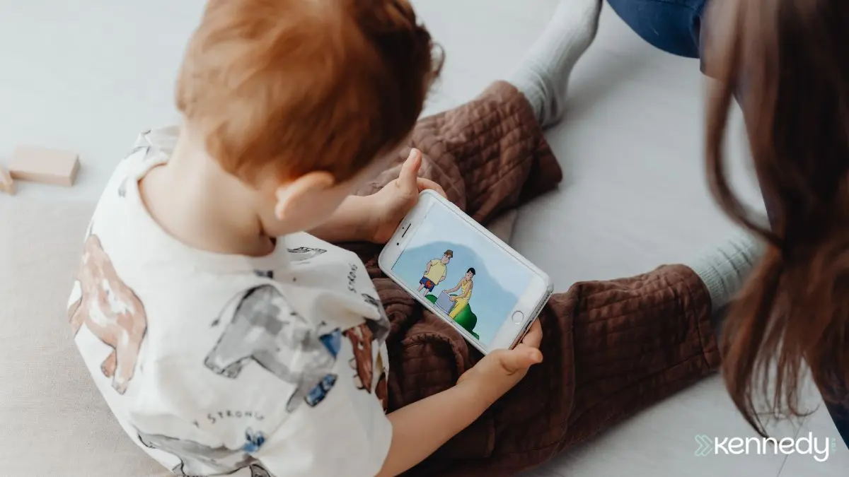 child-watching-video-on-smartphone-while-sitting-with-caregiver