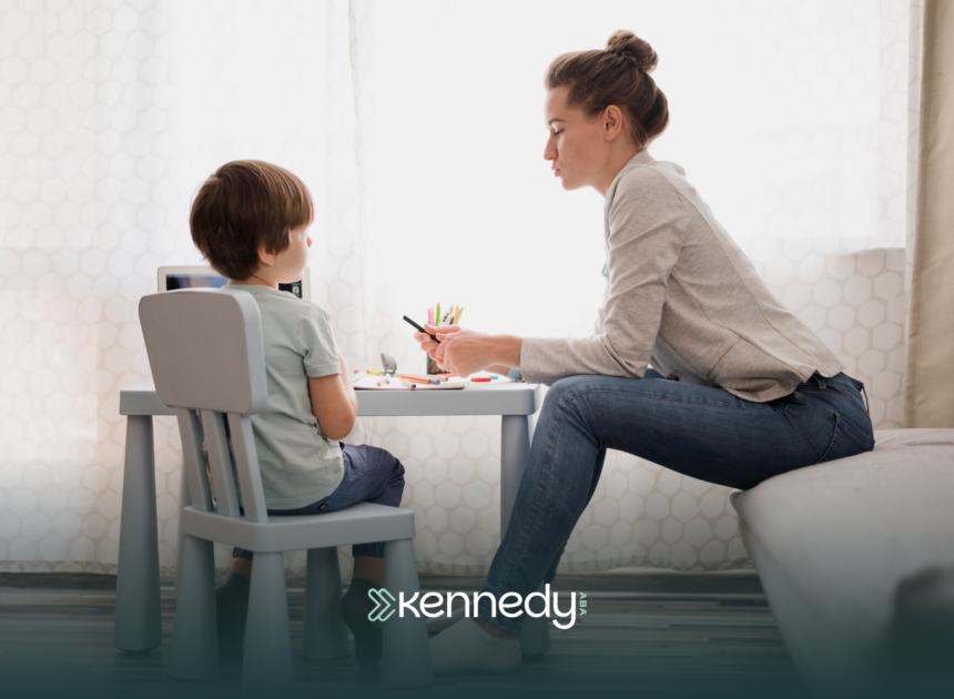 A kid with autism and his ABA therapist sitting at a table while talking during ABA therapy
