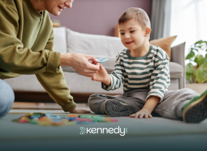 A kid with autism and his ABA therapist sitting on a floor during ABA therapy