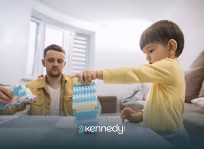 A kid playing with building blocks on a table while his RBT is observing