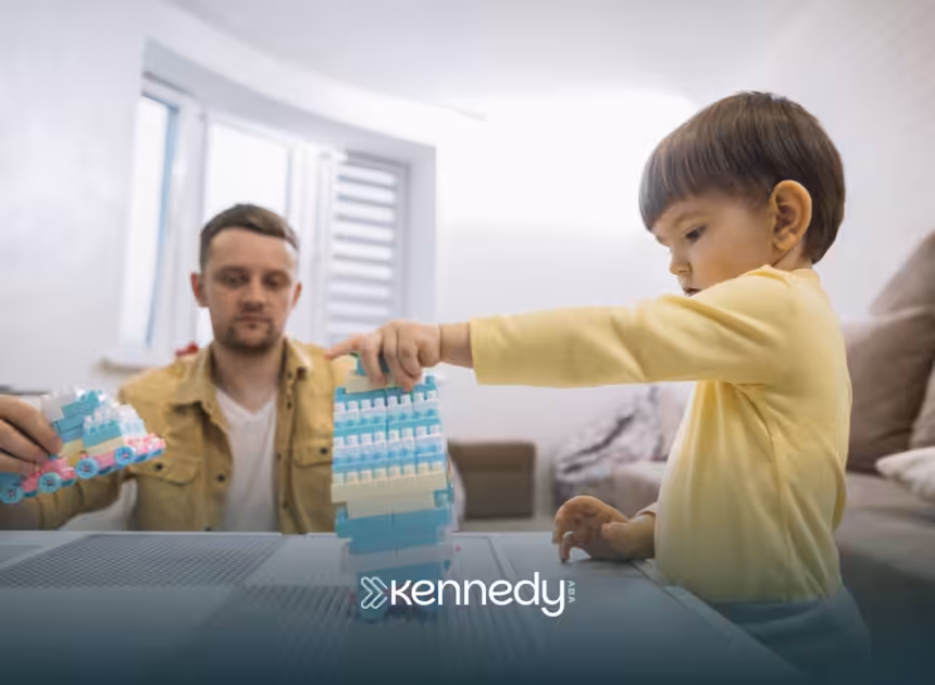 A kid playing with building blocks on a table while his RBT is observing