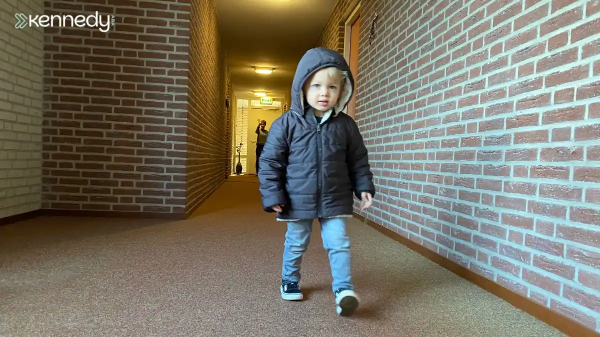 young-child-walking-alone-through-building-hallway-in-coat