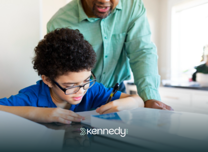 A kid with autism doing an activity while an adult is supervising