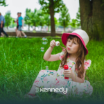 A girl with autism blowing bubbles in a park