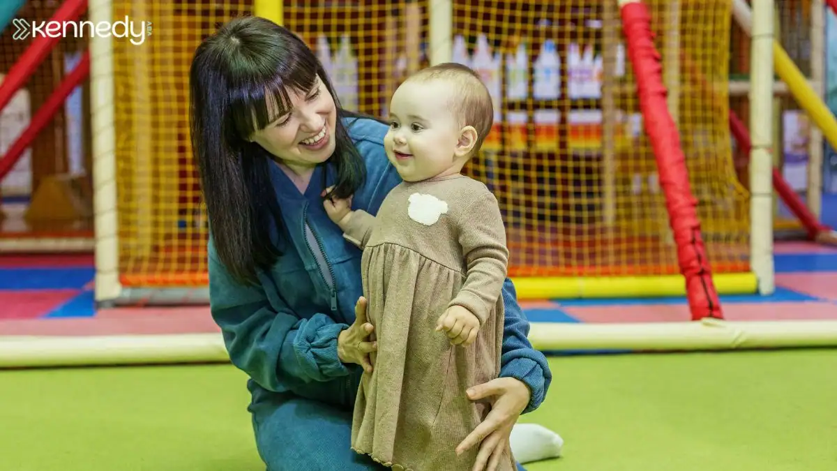 woman-supporting-toddler-during-indoor-playtime