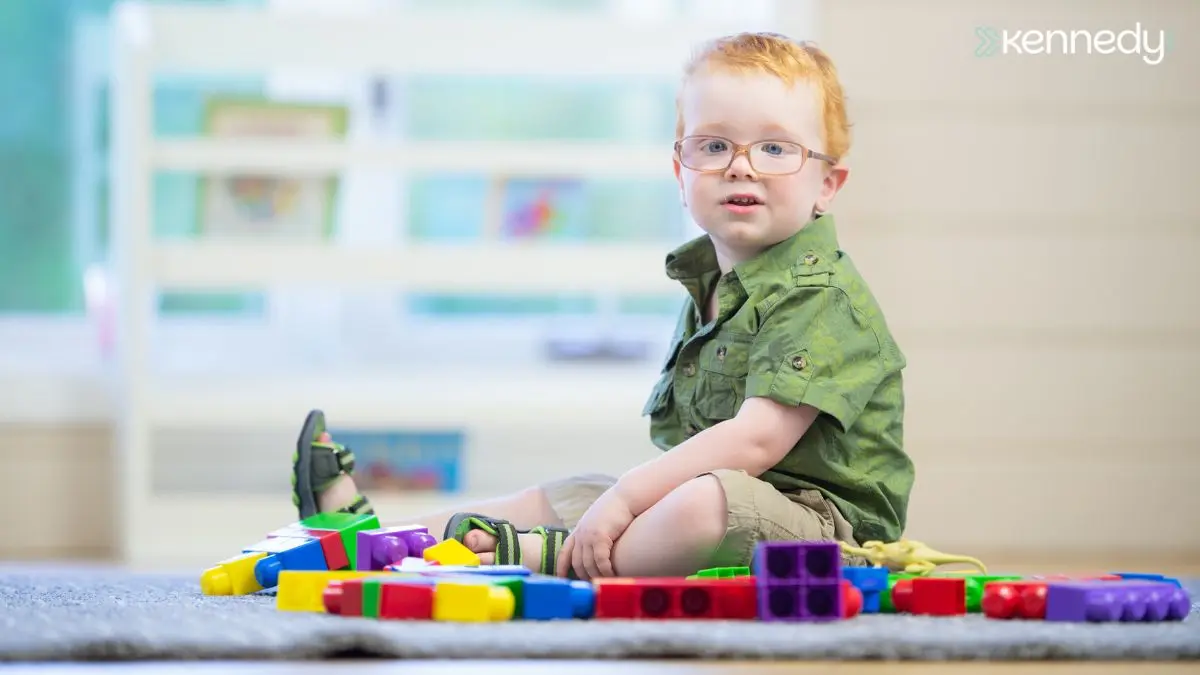 young-child-with-glasses-sitting-by-toy-blocks