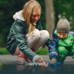 A kid with autism and his mother playing with a puddle outdoors