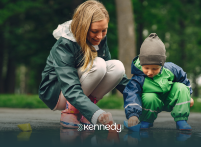 A kid with autism and his mother playing with a puddle outdoors