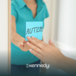 A kid sticking a sticky note with the word "autism" on a mirror