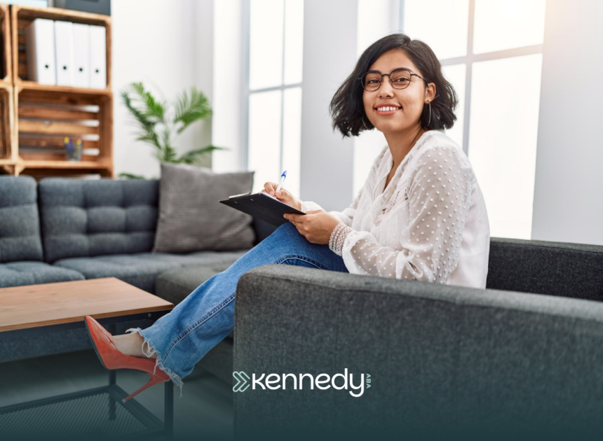 A BCBA holding a clipboard, sitting on a couch