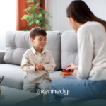 An ABA therapist talking to a kid during ABA therapy in a living room