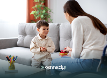 An ABA therapist talking to a kid during ABA therapy in a living room