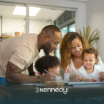 A family of four sitting at a dining table together looking at autism grants