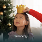 A child sitting at a table with a pretend crown on her head