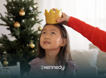 A child sitting at a table with a pretend crown on her head