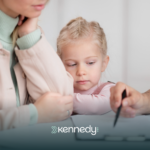 A BCBA explaining the autism evaluation to a parent with her kid watching