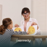 An ABA therapist showing printed smileys to a kid during ABA therapy