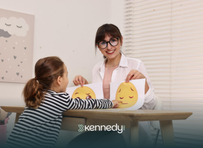An ABA therapist showing printed smileys to a kid during ABA therapy