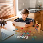 A kid with autism using a mobile tablet while at a table