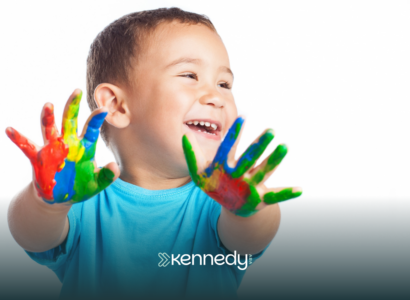A kid with autism happily showing his hands covered in colorful hand paint