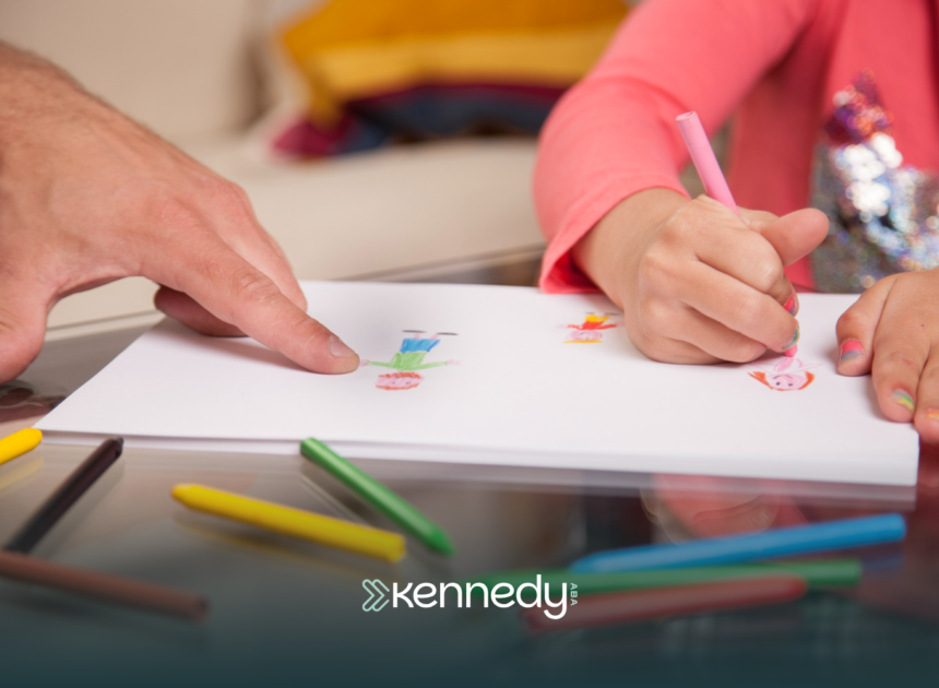 A kid drawing on a paper using coloring pencils with an evaluator guiding her