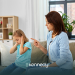 A kid covering her ears, throwing a tantrum, while her ABA therapist comfort her