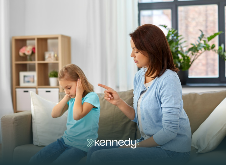 A kid covering her ears, throwing a tantrum, while her ABA therapist comfort her