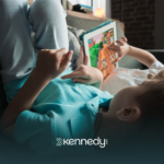 Two kids with autism laying on a couch watching on a tablet