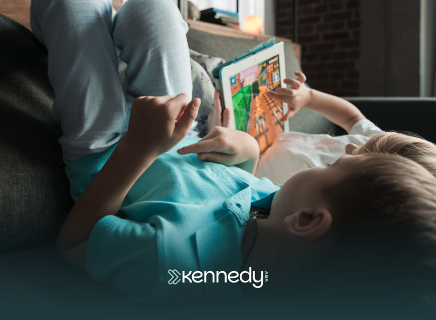 Two kids with autism laying on a couch watching on a tablet