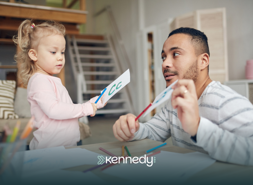 An ABA therapist helping a girl using letter flash cards during ABA therapy