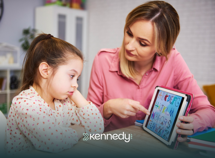 An ABA therapist using a mobile tablet, showing alphabet to a girl during ABA therapy