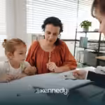 A parent with her child listening to an ABA therapist during ABA therapy