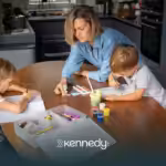 A mom guiding his two kids while doing art activities on a table