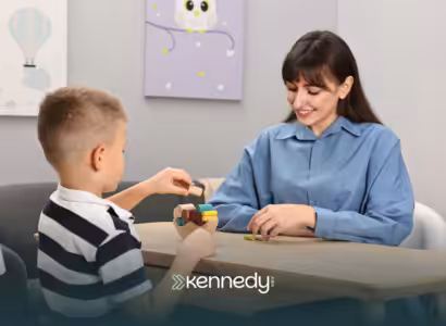 A BCBA observing a child playing with colorful wooden blocks